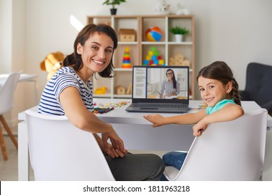 Staying At Home And E-learning Via Interactive School Platform. Portrait Of Happy Smiling Mother And Child Looking At Camera While Watching Educational Video Or During Online Lesson With Private Tutor