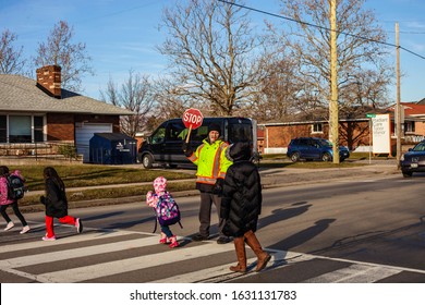 St.Catharines. Ontario/Canada-01.29.2020 Eighty Year Old Crossing Guard.  Older People Always Stay  Young. Children Cross The Street After School. Follow The Rules Of The Road. Pensioners Help Childre