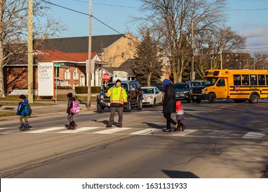 St.Catharines. Ontario/Canada-01.29.2020 Eighty Year Old Crossing Guard.  Older People Always Stay  Young. Children Cross The Street After School. Follow The Rules Of The Road. Pensioners Help Childre