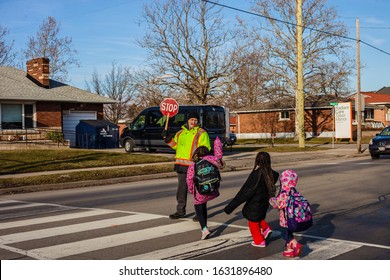 St.Catharines. Ontario/Canada-01.29.2020 Eighty Year Old Crossing Guard.  Older People Always Stay  Young. Children Cross The Street After School. Follow The Rules Of The Road. Pensioners Help Childre