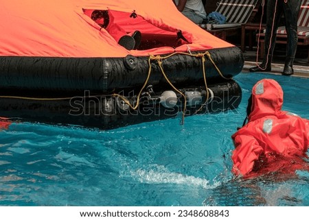 stcw life raft training maritime course in the swimming pool, people wearing waterproof suits