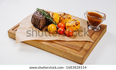 Steak with corn tomatoes cherry tomatoes on a wooden board