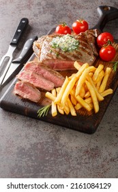 Steak frites is a dish consisting of steak paired with French fries closeup on the wooden board on the table. Vertical