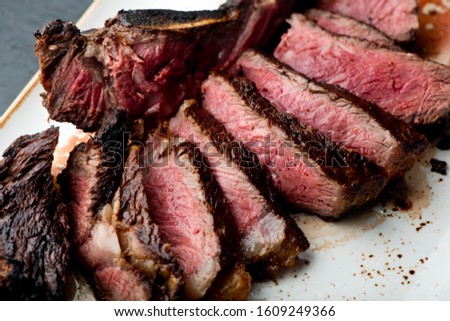 Steak. Grade A, grass fed angus beef. Traditional classic New York steakhouse menu favorite. T-bone steak, bone in, cooked to medium to rare and sliced. 
