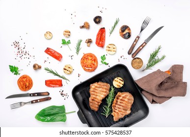 Steak Grill In The Cast Iron Grill Pan On A White Background With A Variety Of Grilled Vegetables Top View. Flat Lay