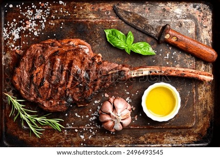 Steak on the bone. Grilled Tomahawk steak with rosemary and spices on a metal plate. Top view.