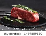 Steak raw. Barbecue Rib Eye Steak or rump steak on rustic table with rosemary