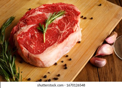 Steak Raw Meat. Black Angus Prime Meat Steaks. Rib Eye Steak, Dry Aged Wagyu Entrecote  Ribeye Steak With Seasoning On Dark Wooden Background. Top View. Rosemary Leaves, Garlic, Salt, Pepper, Red Wine