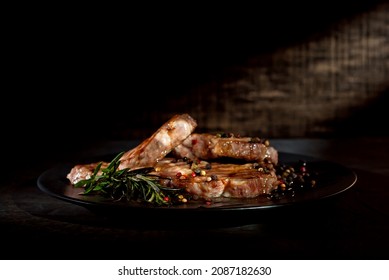 Steak with sauce on a black plate. Meat with spices and rosemary on a dark background. Contrasting light as an artistic effect. - Shutterstock ID 2087182630