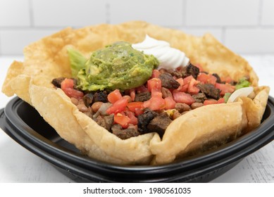 Steak Taco Salad Served In A Crispy Tostada Bowl, Topped With Sour Cream And Guacomole, Will Fill Your Appetite Perfectly.