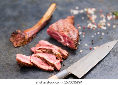 Steakhouse Kitchen. Cowboy Steak. Closeup Of Sliced Grilled Beef Meat, Bone And Knife.