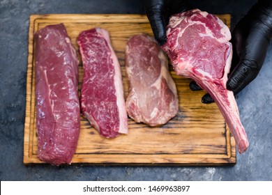 Steakhouse Kitchen. Top View Of Raw Beef Meat Assortment On Wooden Board. Chef Cooking Steaks.