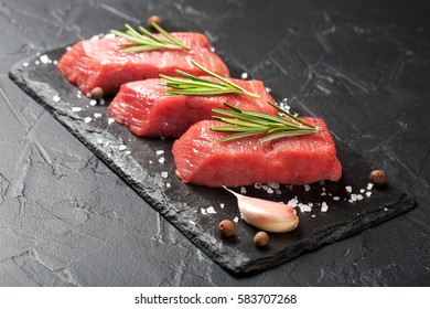 Steaks Raw Meat With Spices On Black Stone Background