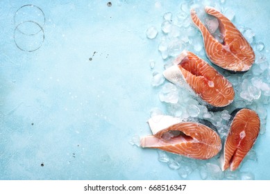 Steaks of raw salmon on ice on a blue slate,stone or metal background.Top view with space for text.