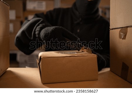 Stealing parcels and damaging the packaging of goods in the warehouse or post office. Man in balaclava and gloves in storehouse. Stealing and problems with the safety of cargo. Close-up