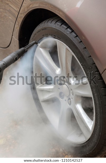 Steam cleaning an alloy wheel of a\
luxury car on a home visiting valet service, England\
UK