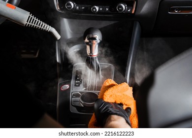 Steam cleaning of gearbox and dashboard in car. Vaping steam. Cleaning individual elements of black leather interior in auto. Creative advert for auto detailing service