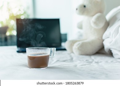 Steam of a coffee cup on the white bed in the morning with nature sun rise, Notebook and teddy bear in Blurred background, Work at home concept, Lifestyle in new normal people in the spread of Covid. - Powered by Shutterstock