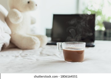 Steam of a coffee cup on the white bed in the morning with nature sun rise, Notebook and teddy bear in Blurred background, Work at home concept, Lifestyle in new normal people in the spread of Covid. - Powered by Shutterstock