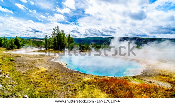 Steam\
coming from the turquoise waters of the Gem Pool hot spring in the\
Upper Geyser Basin along the Continental Divide Trail in\
Yellowstone National Park, Wyoming, United\
States