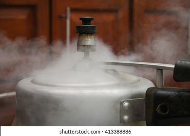 Steam Escaping From Lid Of Pressure Cooker With Reflection Of Modern Kitchen. Indian Style Cooking Rice Or Dhal 