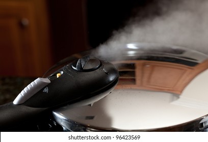 Steam Escaping From Lid Of Pressure Cooker With Reflection Of Modern Kitchen