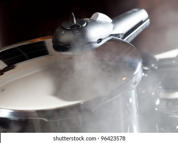 Steam Escaping From Lid Of Pressure Cooker With Reflection Of Modern Kitchen