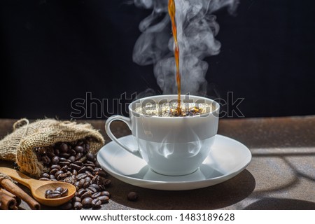 The steam from Pouring coffee into cup , A cup of fresh coffee on rusty metal wall with copy space. A scattering of coffee beans with a cup of coffee. Coarse fabric ,hot food and healthy meal concept