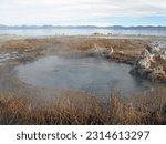 Steam rises from a hot spring against tufa formations on Mono Lake in Lee Vining, California. Eastern Sierra Nevada Mountains in background.   Selective focus
