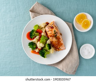 Steam salmon and vegetables, Paleo, keto, fodmap, dash diet. Mediterranean meal with steamed fish. Healthy concept, white plate on table, gluten and lectine free, top view