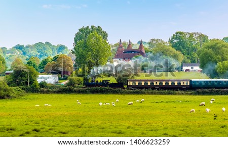 A steam train on the Kent and East Sussex Railway pulls away from to Bodiam Station, Sussex in springtime 