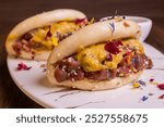 Steamed bao ban filled with beef tartare and mustard and served with BBQ sauce in a grill