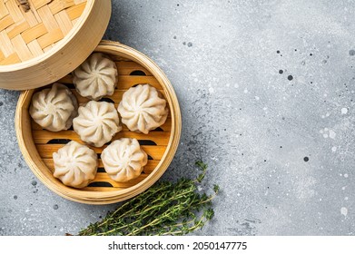 Steamed baozi dumplings stuffed with meat in a bamboo steamer. Gray background. Top view. Copy space