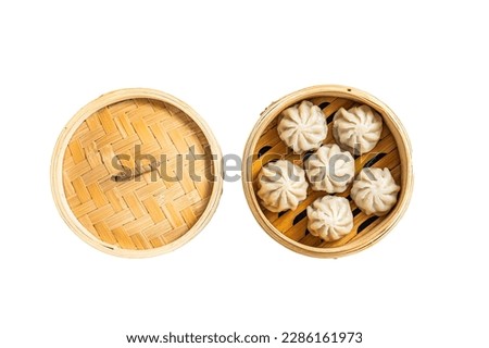 Steamed baozi dumplings stuffed with meat in a bamboo steamer. Isolated on white background
