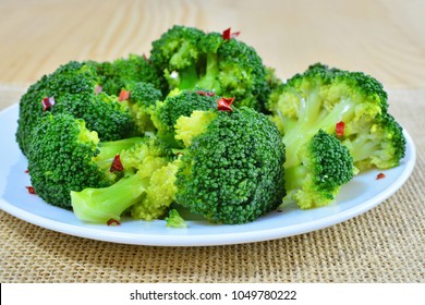 Steamed broccoli with red pepper flakes on plate, macro