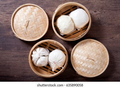 Steamed buns in bamboo steamer on wooden table, chinese dim sum