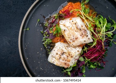 steamed cod fish filet with lettuce as top view on a plate with copy space left