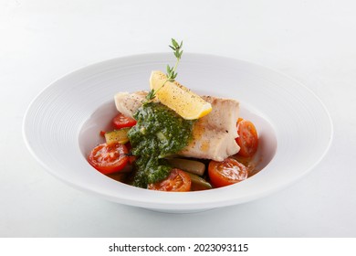 Steamed Cod On Zucchini And Cherry Tomato Pillow With Spinach Mousse, Lemon Wedge And Thyme Sprig In A Round Deep Plate