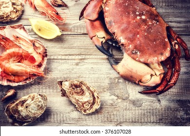 Steamed crab, shrimps and fresh oysters on wooden background. Sea food dinner concept