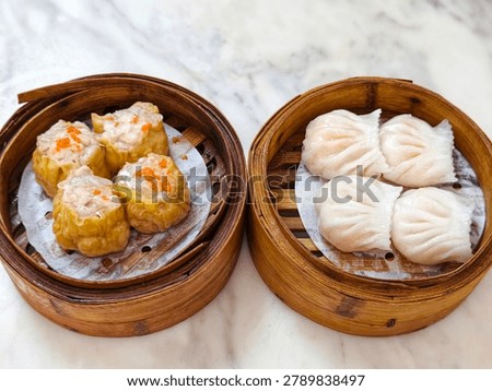 Steamed dim sum assortment featuring siu mai and shrimp dumplings served in traditional bamboo baskets.