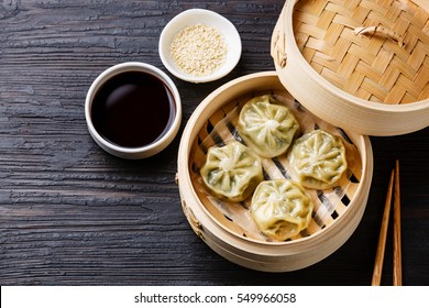 Steamed dumplings Dim Sum in bamboo steamer on black burned wooden background - Shutterstock ID 549966058