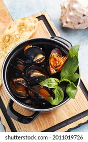 Steamed Mussels In Shells In Tomato Sauce With Fresh Basil Leaves And Roasted Bread Over Blue Concrete Background. Seafood Dinner. Overhead View, Close Up