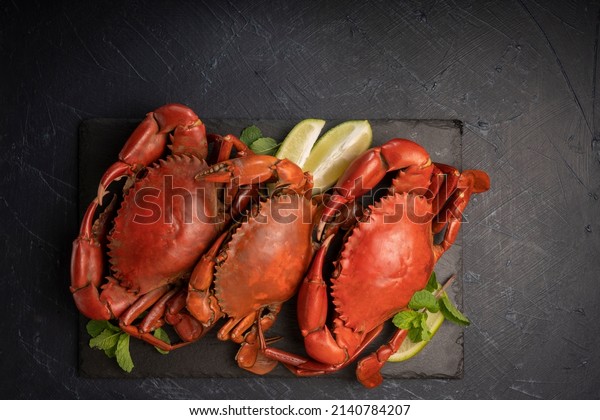 Steamed Red Crab with butter\
and lemon, Boiled Serrated mud crab on black plate on black\
background,