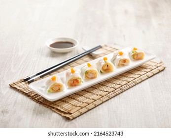 Steamed Rice Roll with Crispy Prawn Filling served in a tray with chopsticks isolated on mat side view on grey marble background