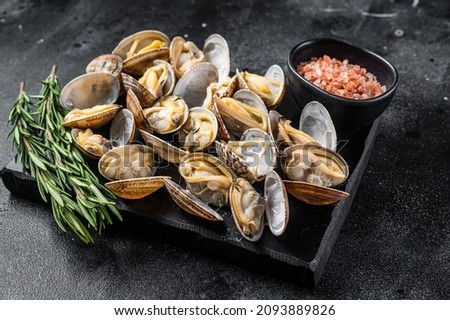 Steamed shellfish Clams with garlic and herbs. Black background. Top view