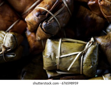 steamed THAI snack, sticky rice with coconut milk and banana double pack wrapped with banana leaf and thin bamboo pieces in traditional steaming pot selective focus blur background street shot photo