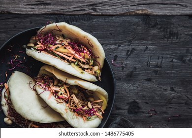 Steamed vegan bao buns with enoki mushrooms, vegetables and peanuts. Dark background with copy space.
