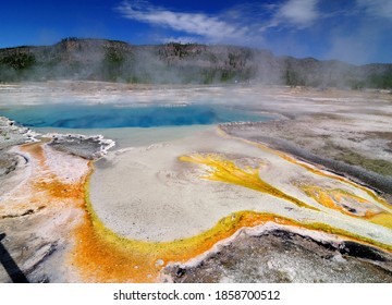 Steaming Beautiful Sapphire Pool At Biscuit Basin Yellowstone National Park On A Sunny Summer Day With A Clear Blue Sky And A Few Clouds