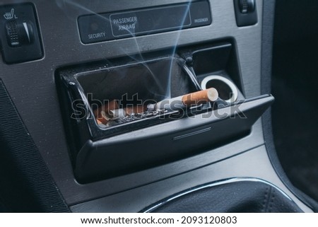 Steaming cigarette in a car ashtray. Smoking in the car