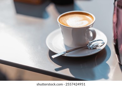 A steaming coffee cup with intricate latte art, set on a sunlit table, evokes warmth and relaxation, offering a cozy atmosphere perfect for leisurely mornings in a stylish cafe. - Powered by Shutterstock